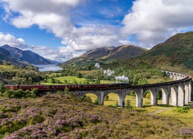 Beruehmtes Glenfinnan Eisenbahnviadukt in Schottland | © Gettyimages:com/catuncia Beruehmten Glenfinnan Eisenbahnviadukt in Schottland. Ein Zug faehrt gerade ueber das gigantische Bauwerk mit atemberaubenden Hintergrund | © Gettyimages:com/catuncia