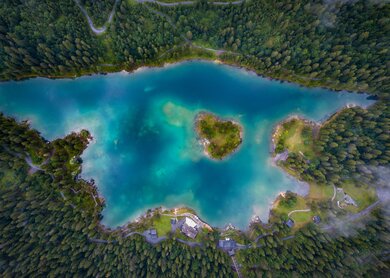Luftaufnahme des malerischen Caumasees umgeben von dichten Wäldern in Graubünden, Schweiz  | © Gettyimages.com/wirestock