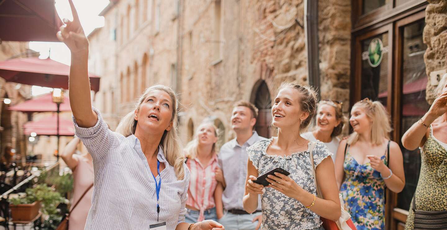 Kleine Reisegruppe auf historischem Stadtrundgang. Sie hört einem Reiseleiter zu, der über die Architektur und die Geschichte spricht. | © © Gettyimages.com/SolStock