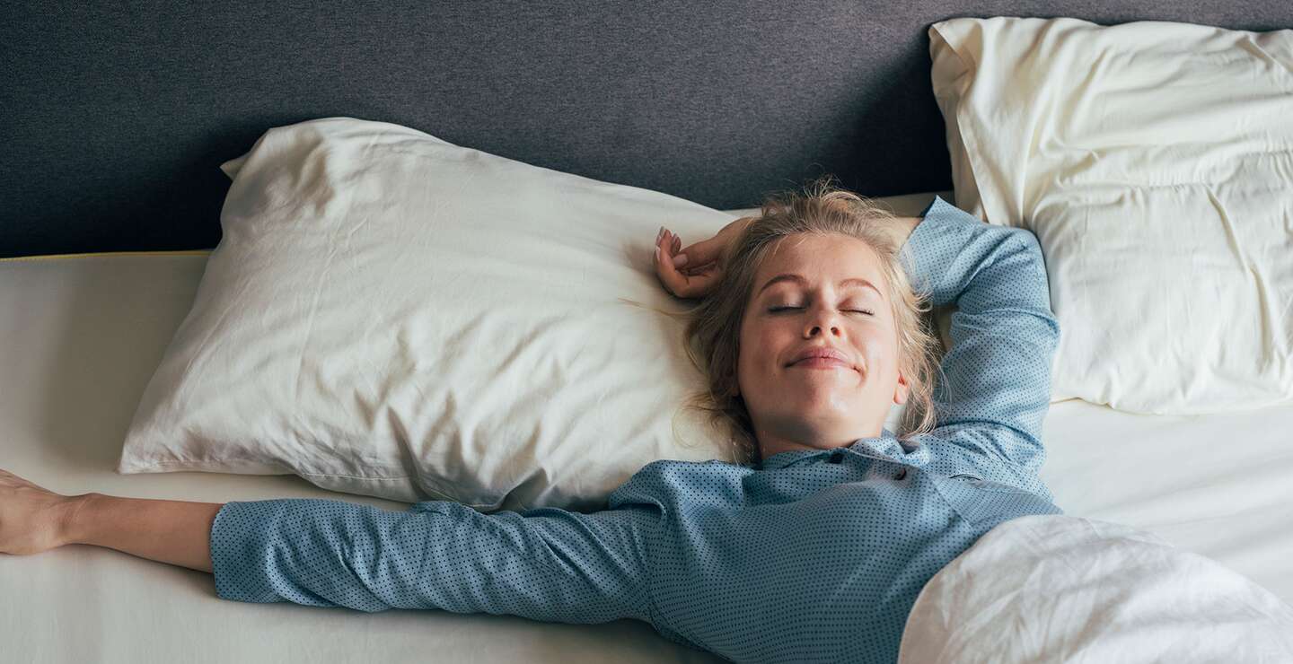 Frau erwacht lächelnd im Hotelbett | © © Gettyimages.com/FreshSplash