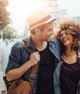 Nahaufnahme eines glücklichen jungen Paares, das Arm in Arm das Stadtleben genießt | © Gettyimages.com/Geber86