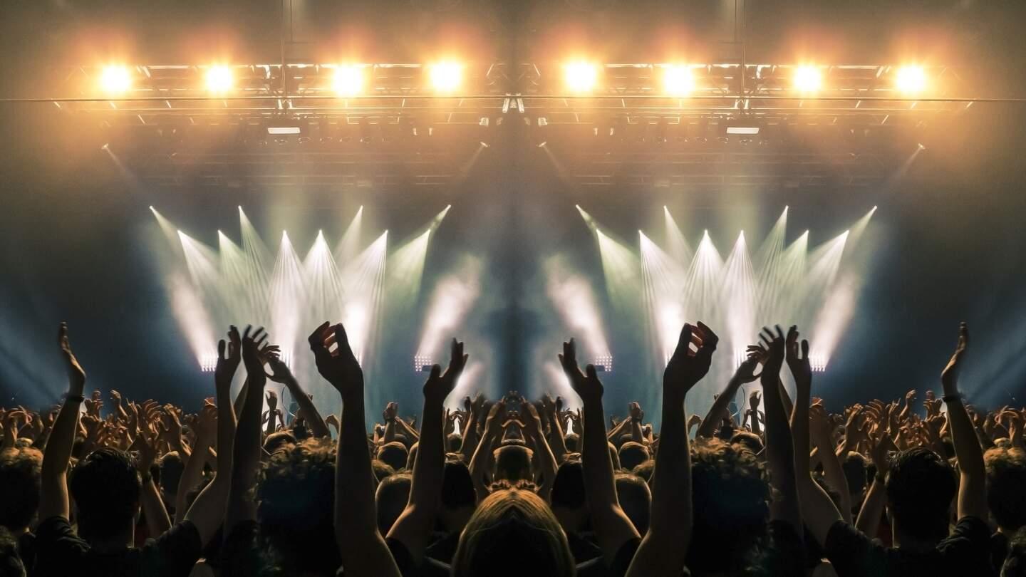 Konzertbuehne, Menschen winken und klatschen, Silhouetten sind sichtbar | © Gettyimages.com/cesareferrari Konzertbuehne, Menschen winken und klatschen, Silhouetten sind sichtbar | © Gettyimages.com/cesareferrari