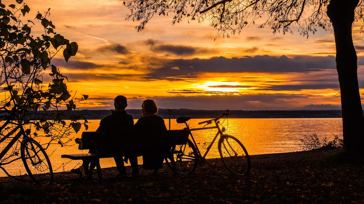 Romantische Pause am Seeufer | © Pixabay.com/blickpixel  Ein Parr macht eine Pause vom radgahren und setzt sich auf eine Bank in der Naehe des Sees,um einen schoenen Sonnenuntergang zu beobachten | © Pixabay.com/blickpixel