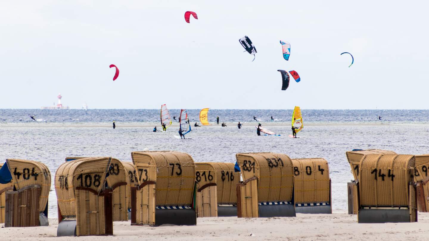 Wind- und Kitesurfer auf dem Wasser mit Strandkörben im Vordergrund | © Gettyimages.com/Florian Graf