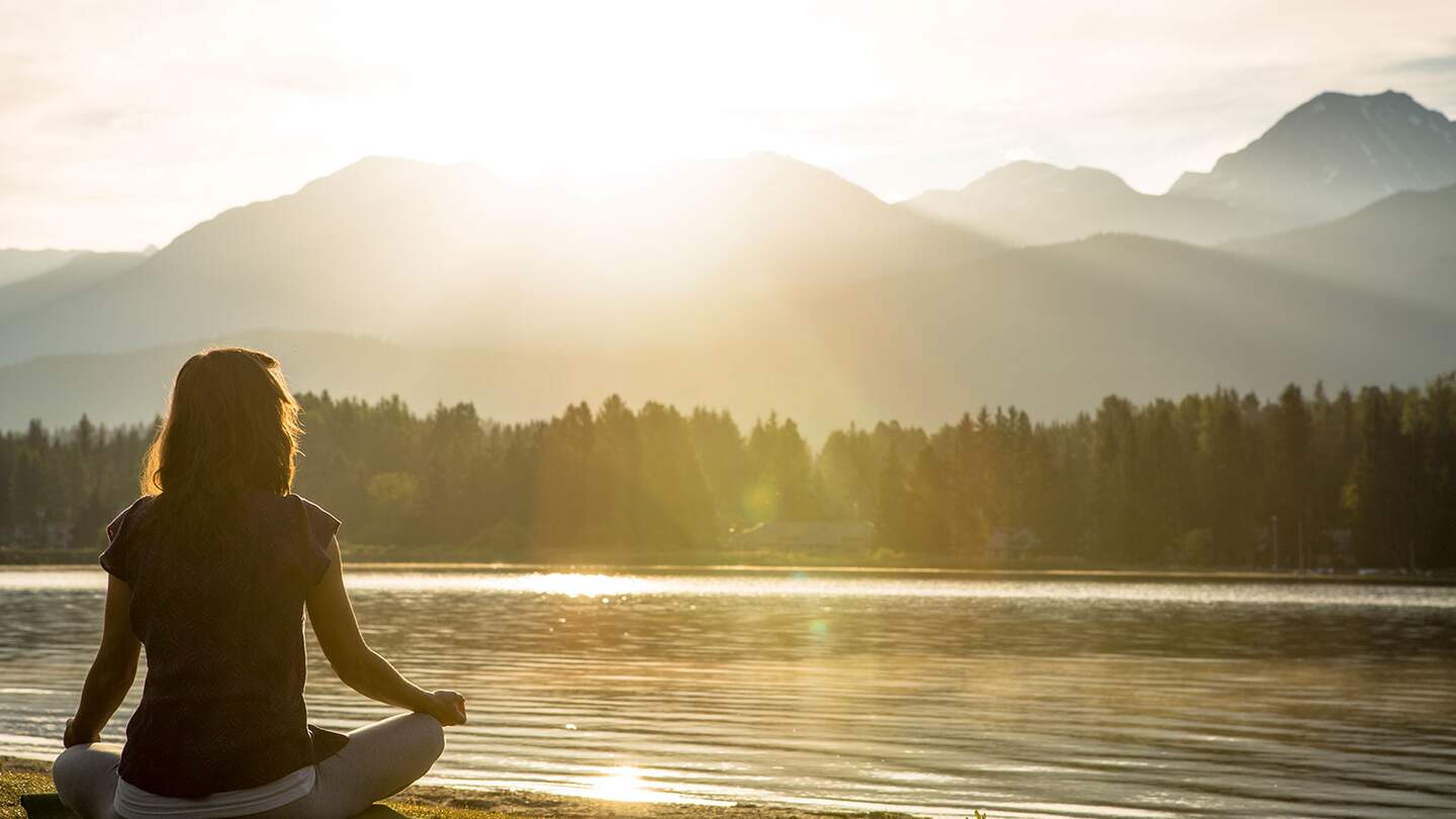 Wellness in den Alpen | © gettyimages.com/VisualCommunications Meditation und Yogapraxis am See bei Sonnenuntergang  | © gettyimages.com/VisualCommunications